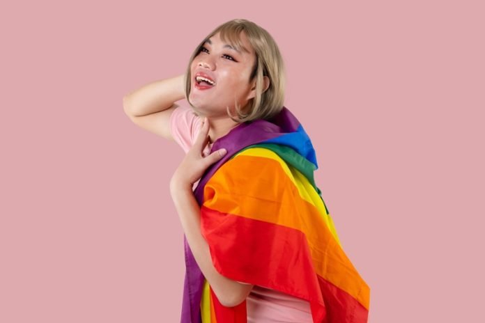 Young Asian transgender LGBT with Rainbow flag isolated over pin